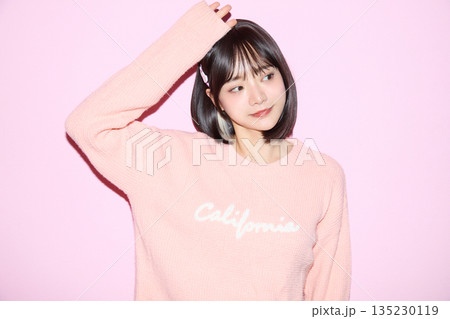ピンク背景でかわいいポーズをする若いアジアの女性ポートレート 135230119