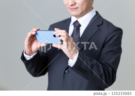 スマホを操作するスーツ姿のミドル男性ビジネスマン 135233083