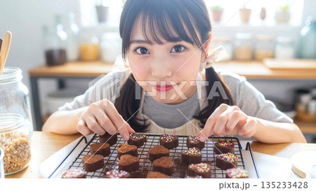 バレンタインの手作りチョコを作る笑顔の女性 キッチンでハートのスイーツを仕上げる様子 2月 贈り物 135233428