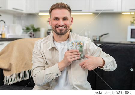 Young man counts cash dollars smiles happy with savings plans dream purchase investment bonus salary Young man counts cash dollars smiles happy with savings plans dream purchase investment bonus salary 135233889