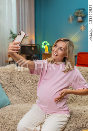 Pregnant woman video calling husband turns smartphone to show belly smiling proudly about baby news 135233925