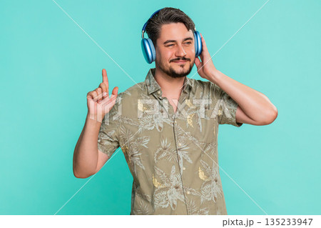 Adult man enjoying music in headphones rhythmically moving head expressing satisfaction dancing 135233947