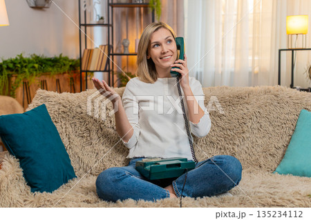 Woman talking on vintage phone at home, emotionally gesturing with hand during intense conversation 135234112