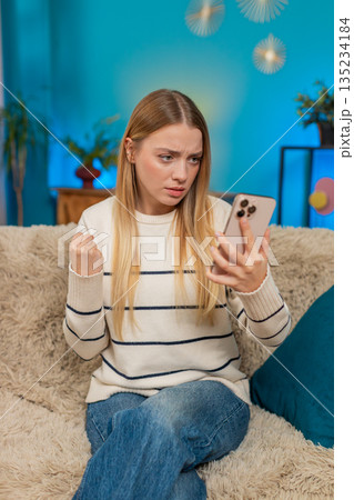 Caucasian woman looking shocked and disappointed after reading bad news or losing lottery on phone Caucasian woman looking shocked and disappointed after reading bad news or losing lottery on phone 135234184