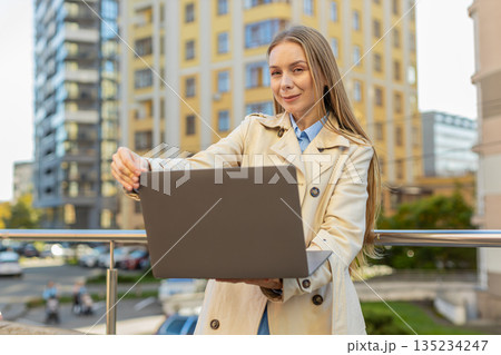 Mature Caucasian businesswoman freelancing remotely, working on laptop netbook in downtown city area Mature Caucasian businesswoman freelancing remotely, working on laptop netbook in downtown city area 135234247