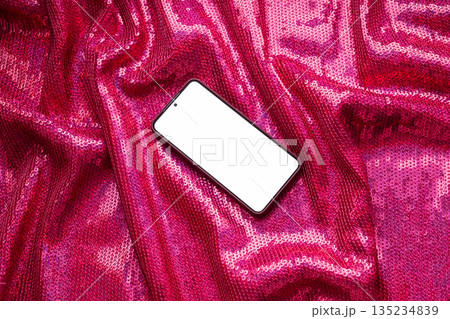 Smartphone with blank screen on sparkly pink sequin fabric backdrop. Smartphone with blank screen on sparkly pink sequin fabric backdrop. 135234839