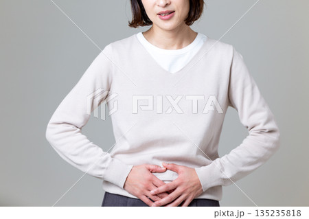 下腹を押さえて腹痛に苦しむミドル女性 下腹を押さえて腹痛に苦しむミドル女性 135235818