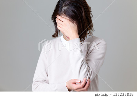 顔を覆って苦しむミドル女性 135235819