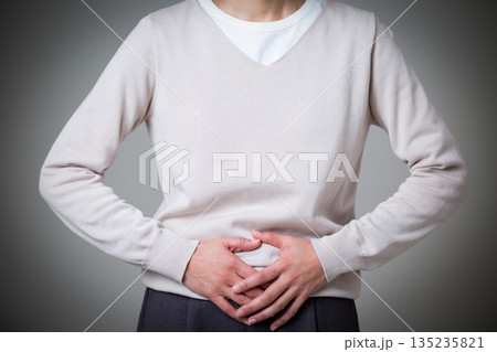 下腹を押さえて腹痛に苦しむミドル女性 135235821