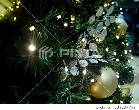 Silver and gold ornaments enhance festive pine branch display Silver and gold ornaments enhance festive pine branch display 135237775