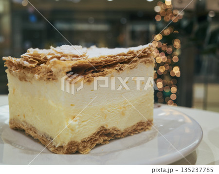 Warm cafe setting featuring sliced cream pastry with powdered sugar 135237785