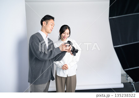 スタジオで女性モデルに写真をみせる男性 スタジオで女性モデルに写真をみせる男性 135238322