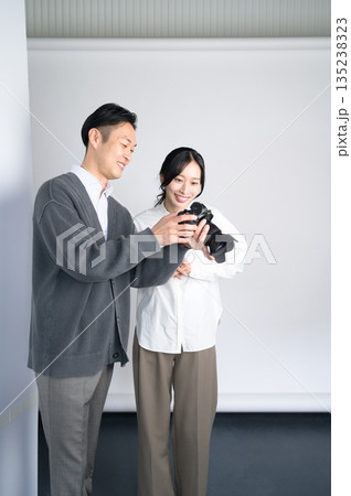 スタジオで女性モデルに写真をみせる男性 135238323