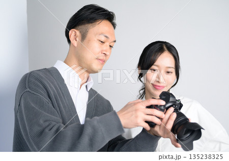 スタジオで女性モデルに写真をみせる男性 スタジオで女性モデルに写真をみせる男性 135238325