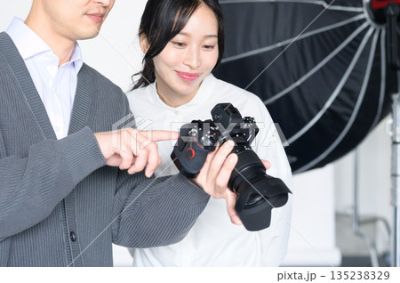 スタジオで女性モデルに写真をみせる男性 135238329