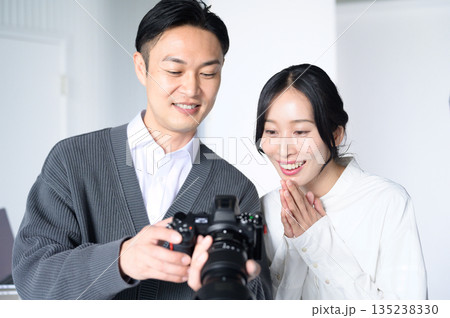スタジオで女性モデルに写真をみせる男性 スタジオで女性モデルに写真をみせる男性 135238330