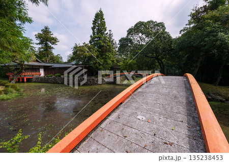 Red curve arching bridge over pond in garden of Usa shrine, Oita Red curve arching bridge over pond in garden of Usa shrine, Oita 135238453