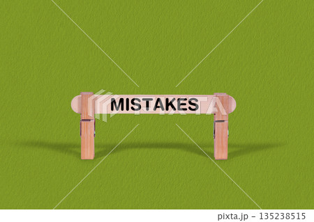 Mistakes symbol. Wooden stick anchored by Clothespins, Cool Green Background. Business and Mistakes concept with copy space 135238515