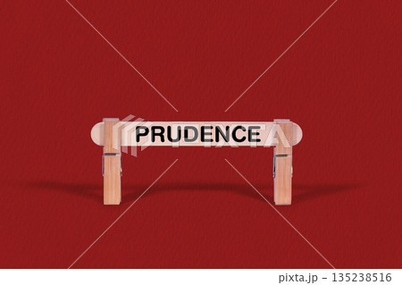 Prudence symbol. Wooden stick braced by Clothespins, beautiful Red Background. Business and Prudence concept with copy space 135238516