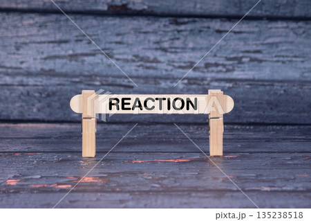 Reaction symbol. Wooden stick fastened by Clothespins, A lightly orange toned grunge wooden background. Business and Reaction concept with copy space 135238518