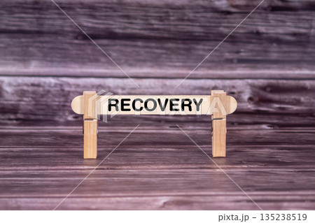 Recovery symbol. Wooden stick held by Clothespins, beautiful Realistic Grunge Wooden Background. Business and Recovery concept with copy space Recovery symbol. Wooden stick held by Clothespins, beautiful Realistic Grunge Wooden Background. Business and Recovery concept with copy space 135238519