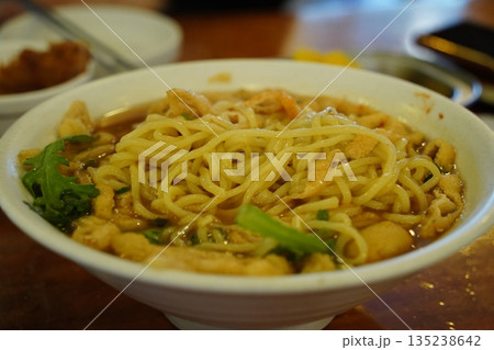 Delicious Korean style udon noodle soup with green vegetables in a white bowl, close up shot Delicious Korean style udon noodle soup with green vegetables in a white bowl, close up shot 135238642