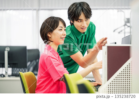 オフィスでデスクワークをするポロシャツ姿の若い男女 135238720