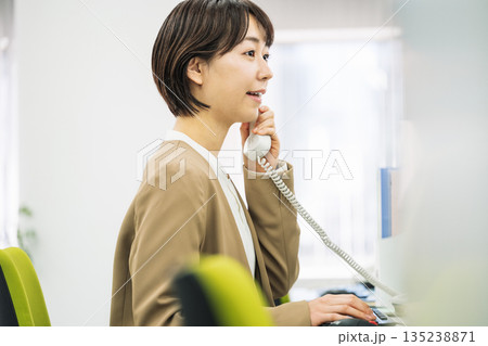 オフィスで電話応対をする若い女性 オフィスで電話応対をする若い女性 135238871