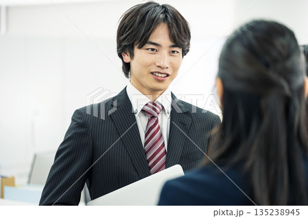 オフィスで女性社員と話す若いビジネスマン 135238945