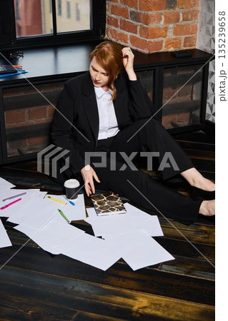 Tired female worker surrounded by documents during late night crisis 135239658