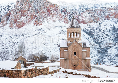 Noravank Monastery stands in snow-covered mountain gorge in Armenia, dramatic red cliffs, winter light, architectural presence, serene atmosphere Noravank Monastery stands in snow-covered mountain gorge in Armenia, dramatic red cliffs, winter light, architectural presence, serene atmosphere 135240667