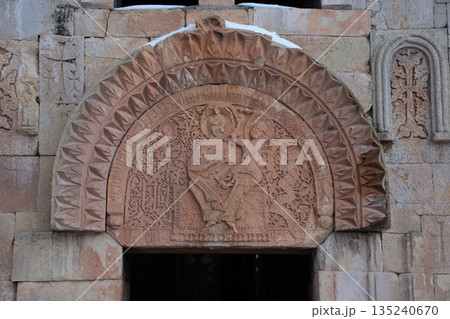 Noravank Monastery facade with carved stone reliefs, arched window stands against sky, snow accents highlighting the historic Armenian architecture Noravank Monastery facade with carved stone reliefs, arched window stands against sky, snow accents highlighting the historic Armenian architecture 135240670