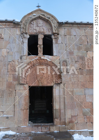 Noravank Monastery facade with carved stone reliefs, arched window stands against sky, snow accents highlighting the historic Armenian architecture Noravank Monastery facade with carved stone reliefs, arched window stands against sky, snow accents highlighting the historic Armenian architecture 135240672