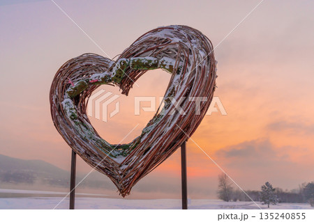 Willow twig installation on the riverbank in winter in February. The heart is a symbol of love on the eve of the Day of all lovers. High quality photo 135240855