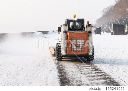 Clearing snow from sidewalks in winter with the help of a mini loader and municipal snow removal equipment. Snowfall and ice, danger of slipping and falling, injury and fractures. High quality photo Clearing snow from sidewalks in winter with the help of a mini loader and municipal snow removal equipment. Snowfall and ice, danger of slipping and falling, injury and fractures. High quality photo 135241021