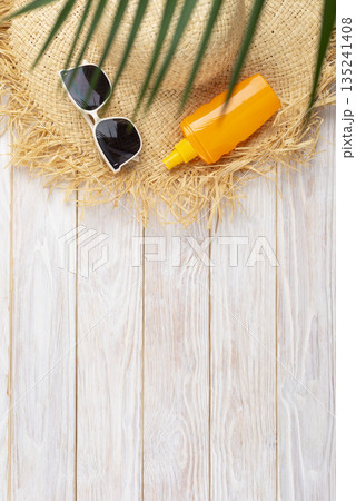 Vacation travel planning simple background of straw hat sunglasses palm leaves and sunblock lotion on white planks flat lay with copy-space Vacation travel planning simple background of straw hat sunglasses palm leaves and sunblock lotion on white planks flat lay with copy-space 135241408