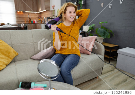 Woman Sitting on Couch Blow Drying Her Hair Woman Sitting on Couch Blow Drying Her Hair 135241986