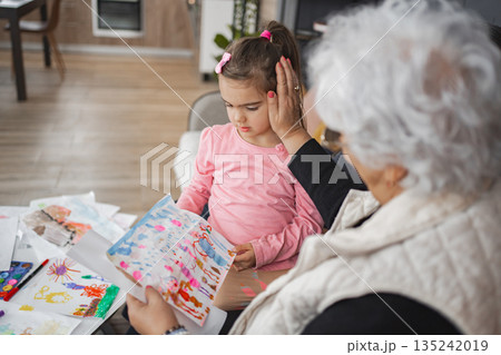 Grandmother admires child's artwork on a cozy afternoon 135242019