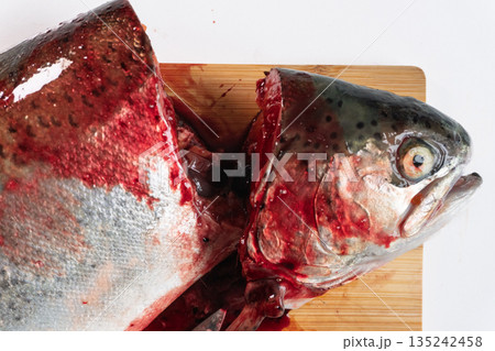 Raw rainbow trout fish head and body cut on a wooden chopping board. Fresh seafood preparation flat lay 135242458