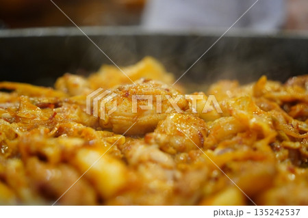 Sizzling Korean spicy stir fried chicken (Dak-galbi) with vegetables on a hot iron plate 135242537