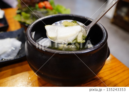 Authentic Korean radish water kimchi (Dongchimi) in a black stone bowl, close up shot Authentic Korean radish water kimchi (Dongchimi) in a black stone bowl, close up shot 135243353