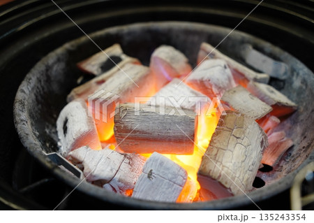 High quality Japanese Binchotan white charcoal glowing in a black metal grill 135243354