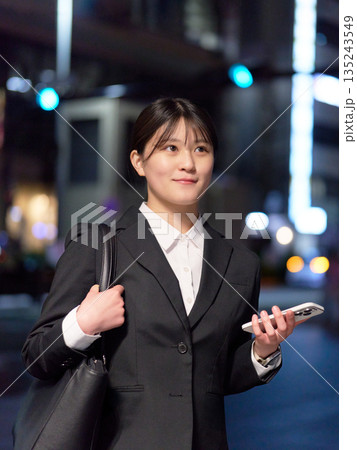 明るい表情で夜の街を歩く若手ビジネスウーマン 明るい表情で夜の街を歩く若手ビジネスウーマン 135243549