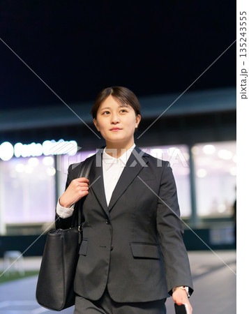 夜の街を歩くスーツ姿の若いビジネスウーマン 135243555