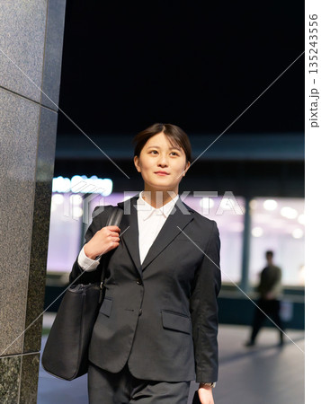 夜の街を歩くスーツ姿の若いビジネスウーマン 135243556