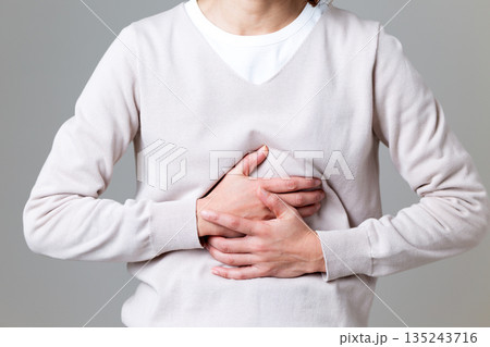 お腹を押さえて腹痛に苦しむミドル女性 135243716