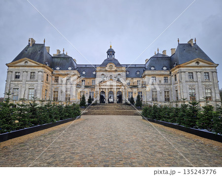 Maincy, France - December 11, 2025: Grand facade of Chateau de Vaux-le-Vicomte with cobblestone courtyard. Beautiful Baroque architecture decorated with small evergreen trees for the winter holidays Maincy, France - December 11, 2025: Grand facade of Chateau de Vaux-le-Vicomte with cobblestone courtyard. Beautiful Baroque architecture decorated with small evergreen trees for the winter holidays 135243776