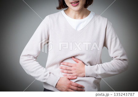 お腹を押さえて腹痛に苦しむミドル女性 135243787