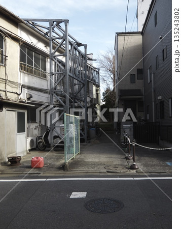 日本の都市の日常を切り取った路地裏の風景。鉄骨の構造物と生活感が漂う住宅街の静かな一角。 日本の都市の日常を切り取った路地裏の風景。鉄骨の構造物と生活感が漂う住宅街の静かな一角。 135243802