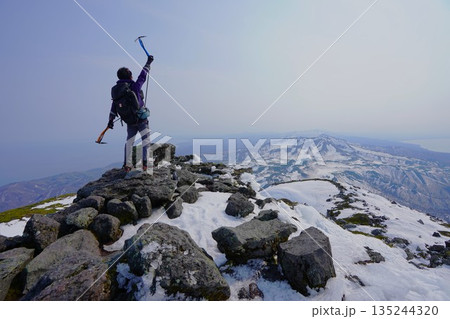 冬季羅臼岳山頂に立つピッケルを持つ登山者 135244320